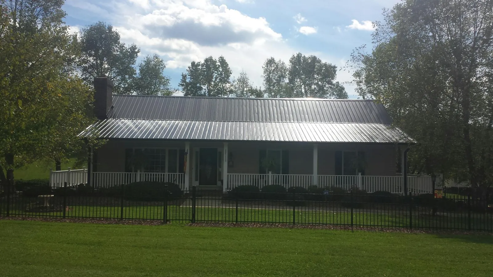 Gray metal roof on a brick ranch with a full width front porch — Gutter Guard Installation work by our crew in Rutherford
