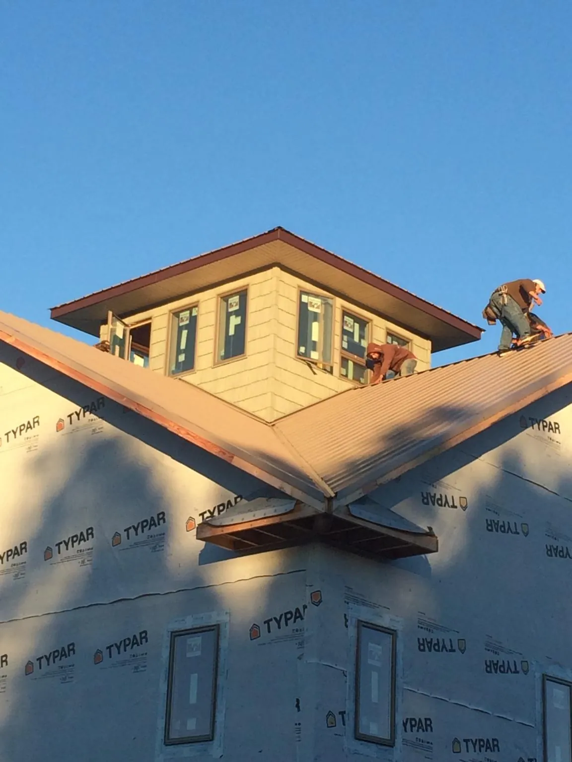 Roofers working around a rooftop cupola on a new metal roof at sunset — Roof Waterproofing in Rutherford by Roofing Brothers